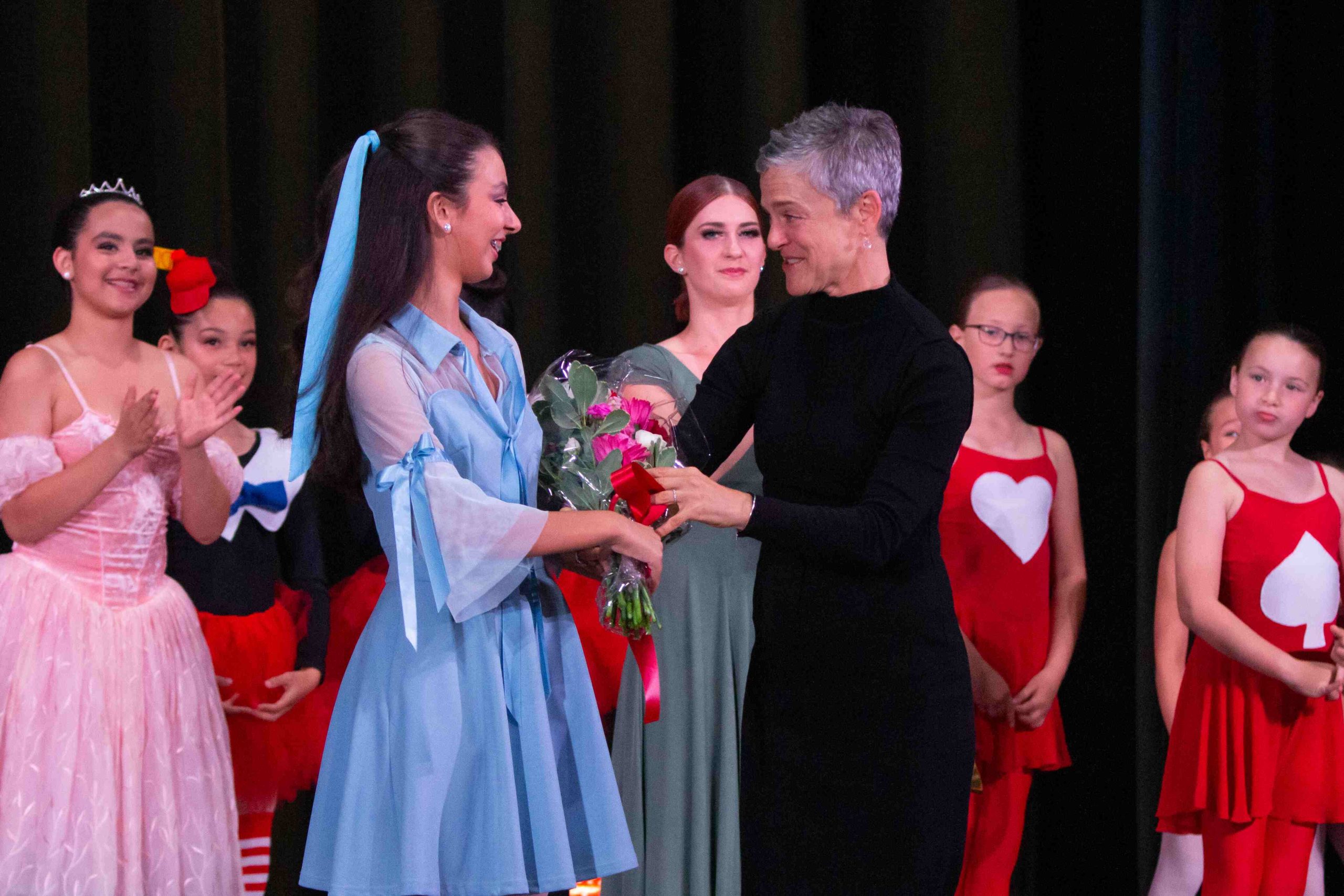 A senior ballerina and artistic director accepts flowers from her star ballerina