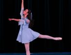 A graceful ballerina poses as Alice in Wonderland with her legs and arms gracefully extended