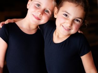 little ballerinas hugging and smiling in studio