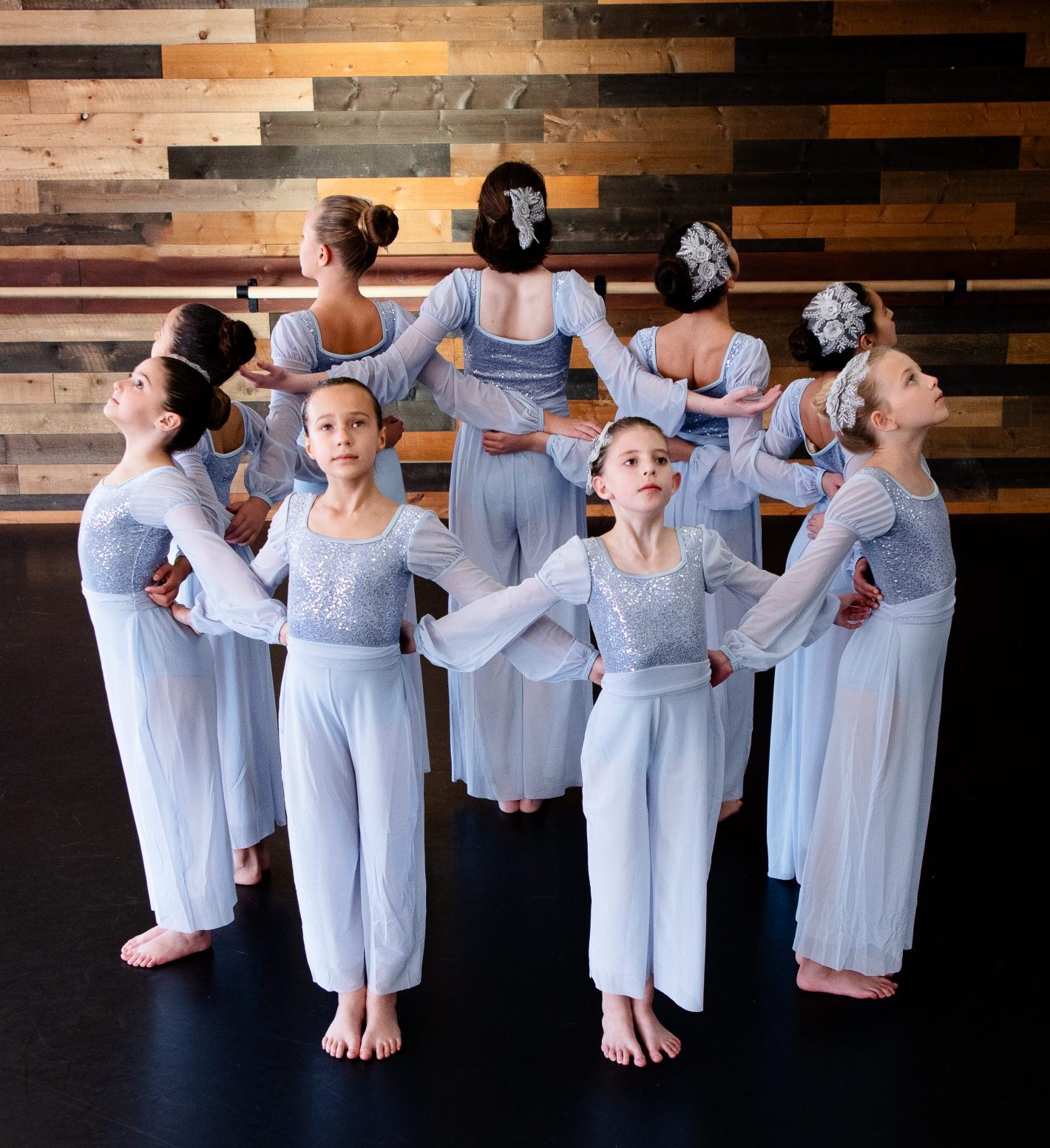 ballet dancers in pale blue costumes pose in a circle