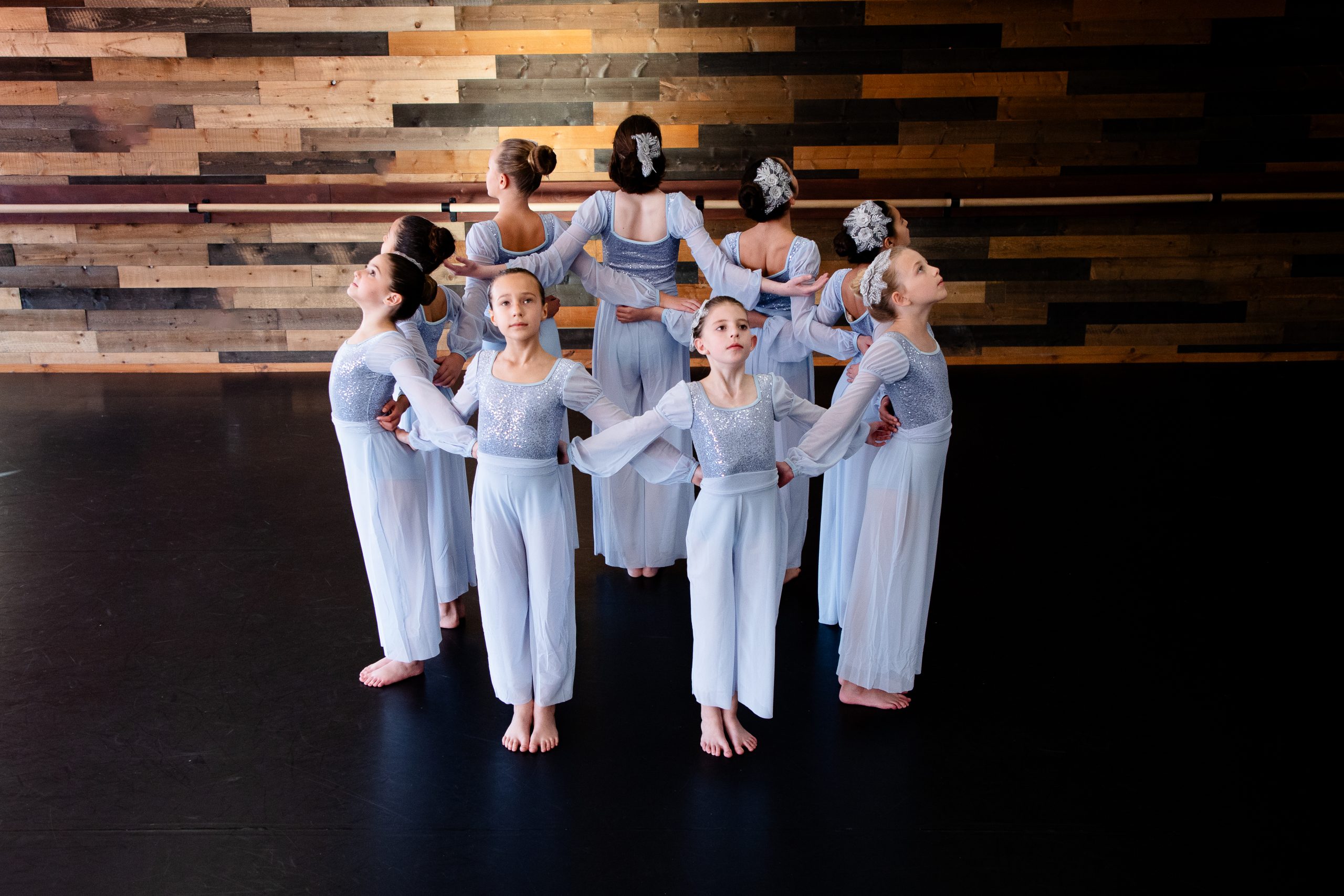 ballet dancers in pale blue costumes pose in a circle